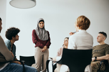 Wall Mural - Young Muslim woman talks about her issues during group therapy meeting at mental health center.