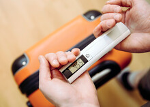 Man Tourist Using Digital Luggage Scale At Home To Weighs Luggage To Avoid Overweight Baggage In Airport Concept. Reduce Traveling Stress.