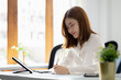 © kamiphotos - Atmosphere in the office of a start-up company, a female employee sits in the office, she is sitting in the sales department where she is making monthly sales summary to make a report to the manager.