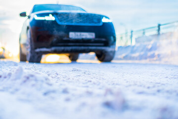 Wall Mural - Winter in the city. The car is moving forward. Sunny day. Snow-covered road. Focus on the snow. Close up view from the level of the road.