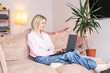 © Tatyana Gladskih - Happy middle aged woman with dog using her laptop at cozy white home