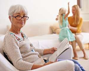 Poster - I love to visit my family. Portrait of a senior woman sitting and reading with her family in the background.