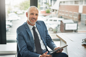 Sticker - Moving forward with the help of technology. Portrait of a mature businessman working on a digital tablet in a modern office.