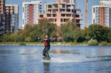 Wakeboarder Surfing On Lake. Young Man Surfer Having Fun Wakeboarding In The Cable Park. Water Sport, Outdoor Activity Concept.