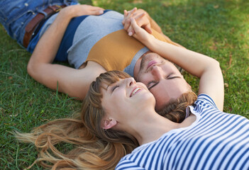 Wall Mural - Happy and in love. Shot of a happy young couple lying in the park.