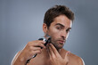 Grooming for the modern man. A young man shaving with an electric razor.