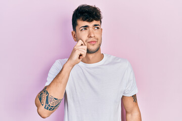 Poster - Young hispanic man wearing casual white t shirt thinking concentrated about doubt with finger on chin and looking up wondering