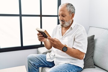 Canvas Print - Senior grey-haired man smiling confident looking picture at home