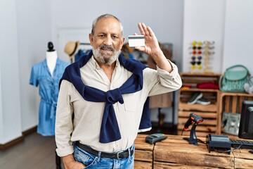 Poster - Senior grey-haired man smiling confident holding credit card at clothing store