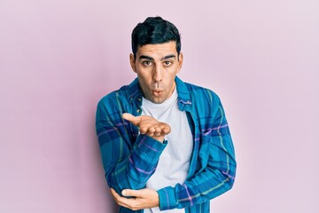 Wall Mural - Handsome hispanic man wearing casual clothes looking at the camera blowing a kiss with hand on air being lovely and sexy. love expression.
