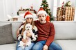 © Krakenimages.com - Young couple of wife and husband sitting on the sofa wearing christmas hat at home scared and amazed with open mouth for surprise, disbelief face