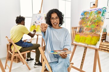 Sticker - Young hispanic woman at art studio pointing to you and the camera with fingers, smiling positive and cheerful