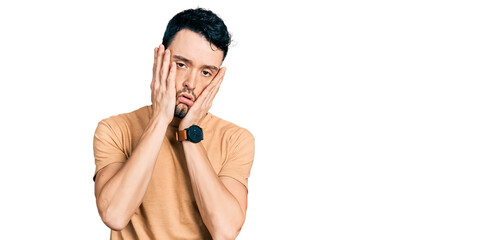 Canvas Print - Hispanic man with beard wearing casual t shirt tired hands covering face, depression and sadness, upset and irritated for problem