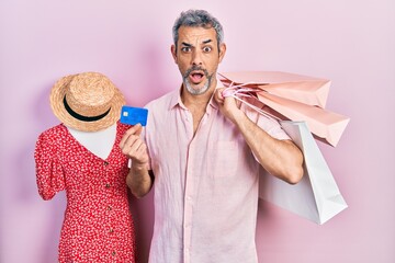 Sticker - Handsome middle age man with grey hair holding shopping bags and credit card afraid and shocked with surprise and amazed expression, fear and excited face.