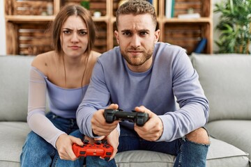 Sticker - Young caucasian couple concentrated playing video game at home.