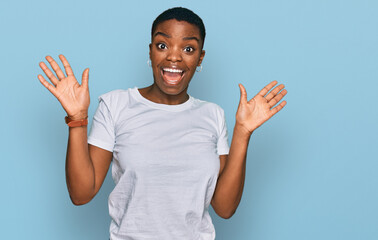 Young african american woman wearing casual white t shirt celebrating crazy and amazed for success with arms raised and open eyes screaming excited. winner concept