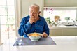© Krakenimages.com - Senior man with grey hair eating pasta spaghetti at home feeling unwell and coughing as symptom for cold or bronchitis. health care concept.