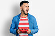 © Krakenimages.com - Young hispanic man with beard playing video game holding controller angry and mad screaming frustrated and furious, shouting with anger. rage and aggressive concept.