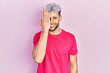Young hispanic man with modern dyed hair wearing casual pink t shirt covering one eye with hand, confident smile on face and surprise emotion.