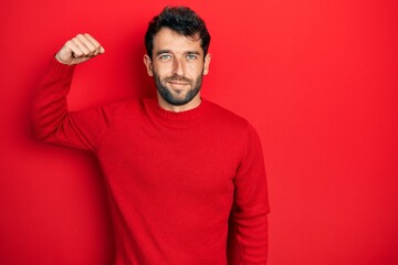 Sticker - Handsome man with beard wearing casual red sweater strong person showing arm muscle, confident and proud of power