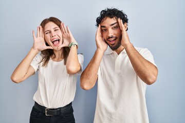 Sticker - Young couple wearing casual clothes standing together smiling cheerful playing peek a boo with hands showing face. surprised and exited