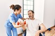 © Krakenimages.com - Middle age man and woman having rehab session using dumbbell sitting on wheelchair at physiotherapy clinic