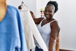© Krakenimages.com - Young african american woman customer holding clothes of rack at clothing store