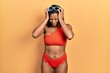 © Krakenimages.com - Young african american girl wearing bikini suffering from headache desperate and stressed because pain and migraine. hands on head.