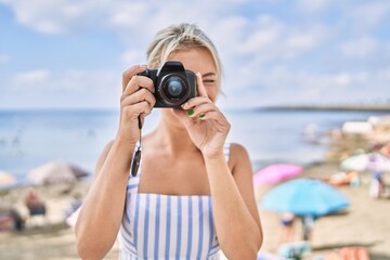 Poster - Young blonde girl smiling happy using camera at the beach.