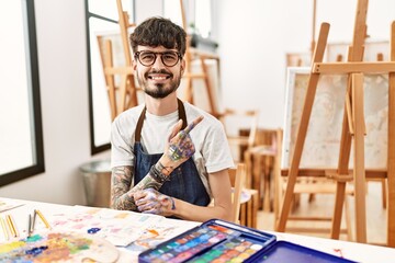 Poster - Hispanic man with beard at art studio cheerful with a smile of face pointing with hand and finger up to the side with happy and natural expression on face