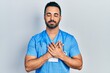 © Krakenimages.com - Handsome hispanic man with beard wearing doctor uniform smiling with hands on chest with closed eyes and grateful gesture on face. health concept.