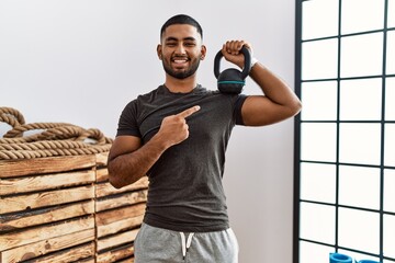 Canvas Print - Young indian man wearing sportswear using dumbbells smiling happy pointing with hand and finger