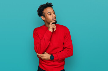 Young african american man with beard wearing casual winter sweater with hand on chin thinking about question, pensive expression. smiling with thoughtful face. doubt concept.