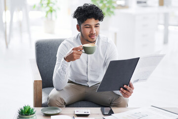 Wall Mural - Staying updated with all his paperwork. Shot of a young businessman drinking coffee while going through paperwork in an office.