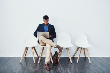 Poster - Focused men always achieve everything they set out to achieve. Full length studio shot of a young businessman sitting down on a chair and using his laptop.