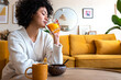 © Daniel - Relaxed African American woman drinks orange juice for breakfast at home. Copy space.