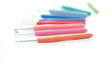 Blurred colorful crochet hooks in different sizes for knitting isolated on white background