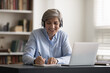 60s woman sit at table listen audio course through headphones smile enjoy study process self-education, online class with tutor, take notes, gain new knowledge, improve language skill use tech concept