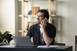 © fizkes - Happy handsome millennial businessman making phone call to client, consulting customer support center, speaking on cellphone at laptop computer at office workplace, looking away, smiling