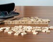 get the scoop word or concept represented by wooden letter tiles on a wooden table with glasses and a book