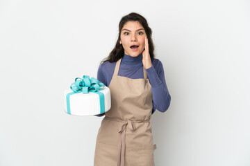 Pastry Russian chef holding a big cake isolated on white background with surprise and shocked facial expression