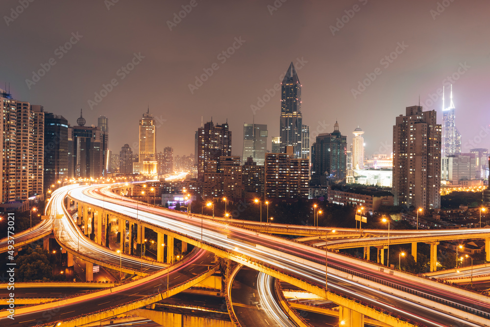 Urban overpasses with lights on at night and the urban background in the distance