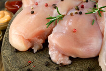 Fresh Raw Chicken Breast Fillets Sprinkled With Peppercorns, Rosemary And Sauces, On Round Wooden Board.