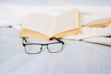 Poster - A good read starts with good reading glasses. Still life shot of reading glasses and books lying on a bed.