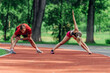 © qunica.com - Young couple stretching before starting their morning jogging routine on a tartan track at the park.
