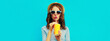 Portrait of stylish young woman drinking a fresh juice wearing a summer straw hat and striped t-shirt on blue background