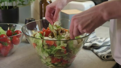 Wall Mural - Female hands mixing green vegetable salad in glass bowl at kitchen, Healthy eating and diet concept