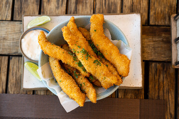 Fresh fried Brazilian tilapia fish strips with lime and tartar sauce known as isca de peixe. Traditional Brazilian appetizer. Selective focus