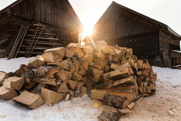 winter preparation. stacking firewood in front of 2 houses during sunset. pile of firewood loggs. fi