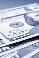 Wall Mural - American paper money. Several one hundred dollar banknotes lie on textured surface. Focus on the number 100. Savings economy and the US dollar. Fed and federal rate. Blue tinted vertical illustration